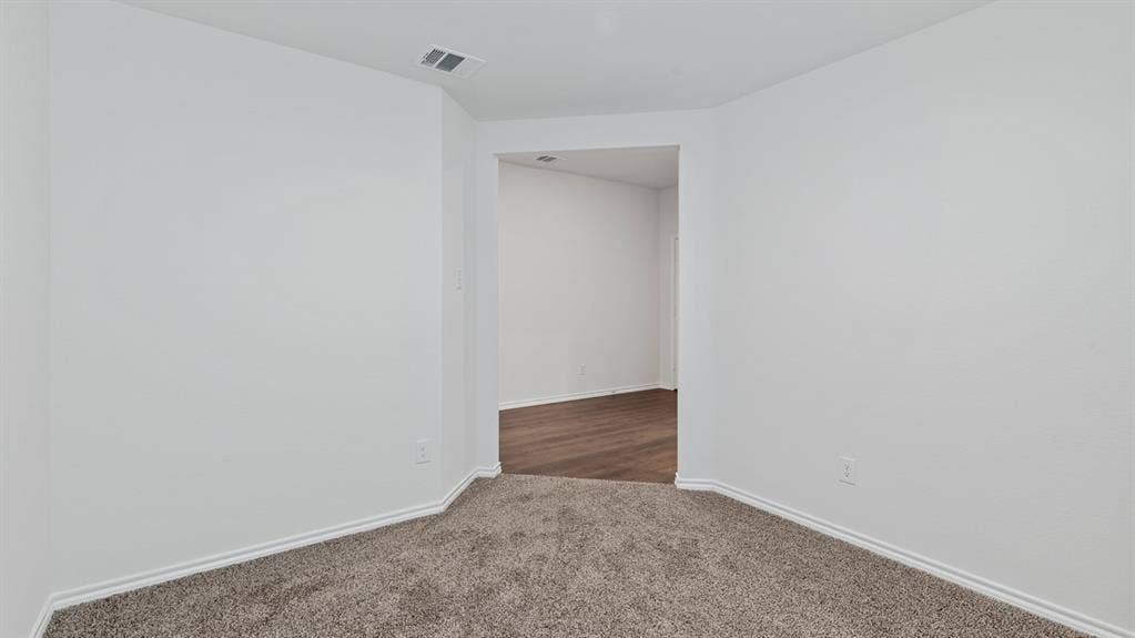 4028 Ripplewood Drive, Lindale, TX 75771 Carpeted room with white walls, white trim, and a doorway opening to a room with wood-finish flooring