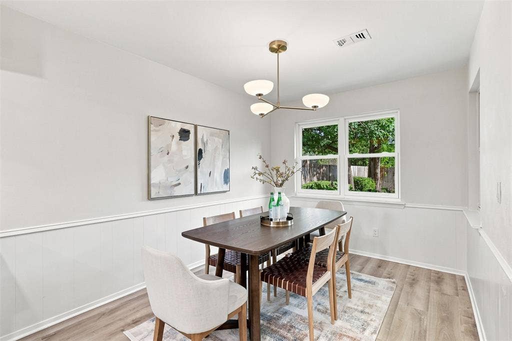 Wood-finish flooring, white paneled wainscoting, white walls, and a multi-globe chandelier