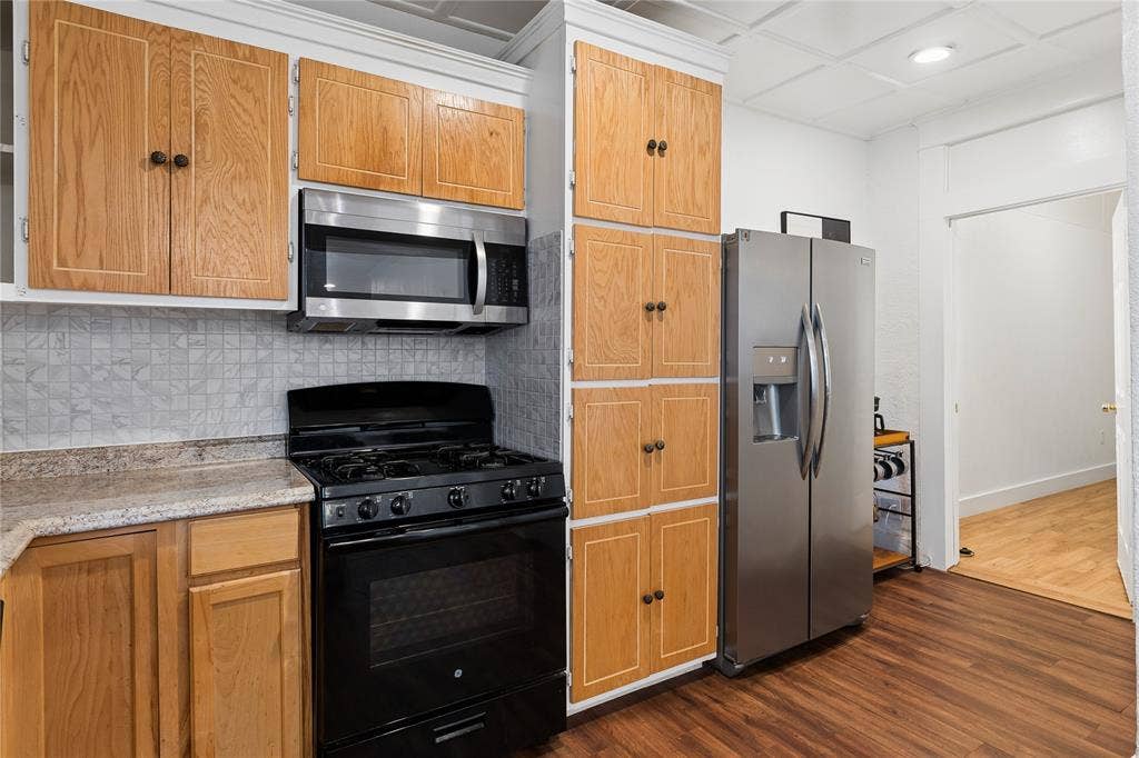 4112 Congress Avenue, Dallas, TX 75219 Wood-finish flooring with oak-finish cabinetry, stainless steel microwave, black range, and stainless steel refrigerator