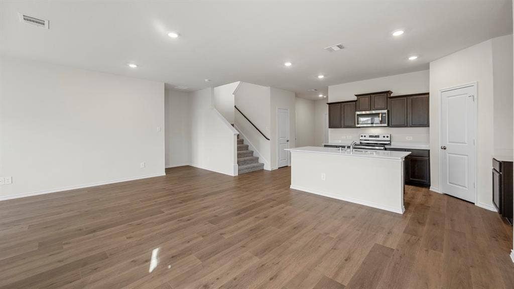 5028 Shumard Drive, Lindale, TX 75771 Expansive living area with wood-finish flooring, recessed lighting, and a staircase featuring carpeted treads and a dark handrail