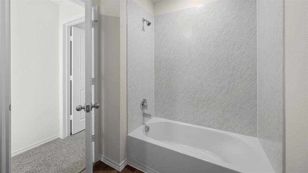 5028 Shumard Drive, Lindale, TX 75771 Bathtub with integrated shower, chrome fixtures, and a textured wall surround