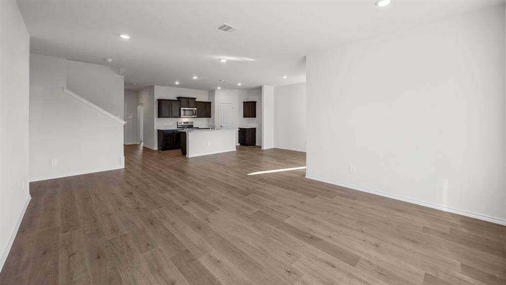 5028 Shumard Drive, Lindale, TX 75771 Wood-finish flooring throughout, recessed lighting, and a kitchen featuring a central island, dark cabinetry, and stainless steel appliances
