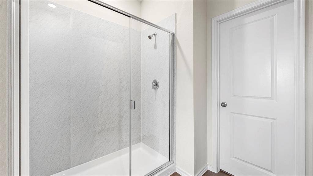 5028 Shumard Drive, Lindale, TX 75771 Enclosed shower with clear glass sliding door, integrated shower head, and light-toned wall paneling