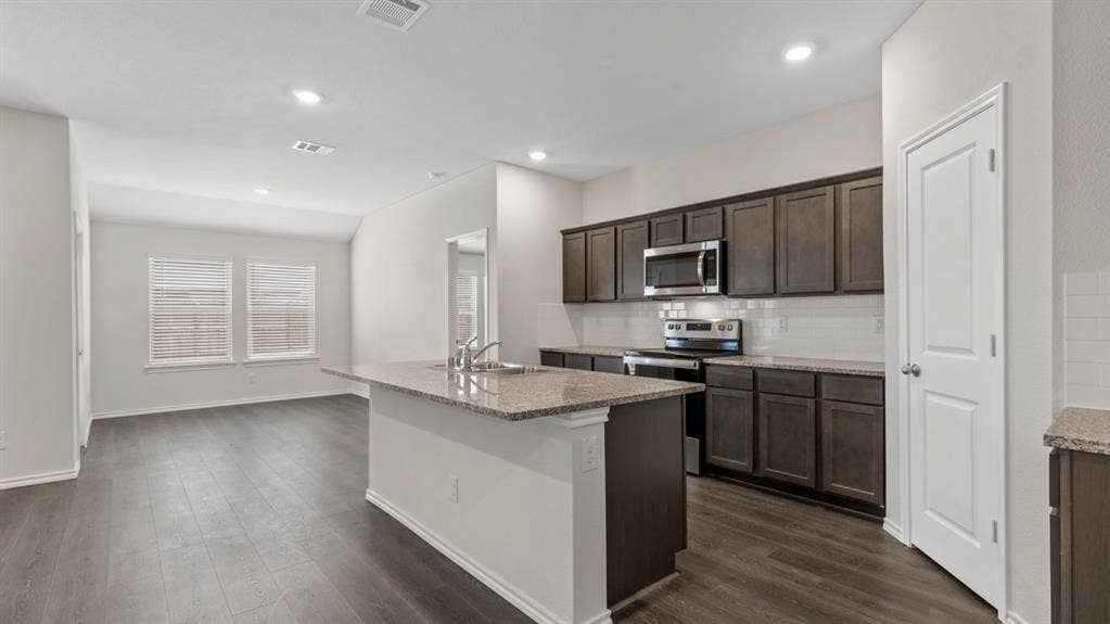 3037 Hidden Valley Drive, Lindale, TX 75771 Kitchen featuring wood-finish flooring, dark wood-finish cabinetry, stainless steel appliances, light-toned countertops, and a subway tile backsplash