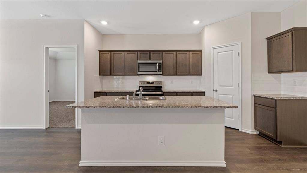 3037 Hidden Valley Drive, Lindale, TX 75771 Kitchen featuring an island with a sink, granite countertops, wood-finish flooring, and recessed lighting