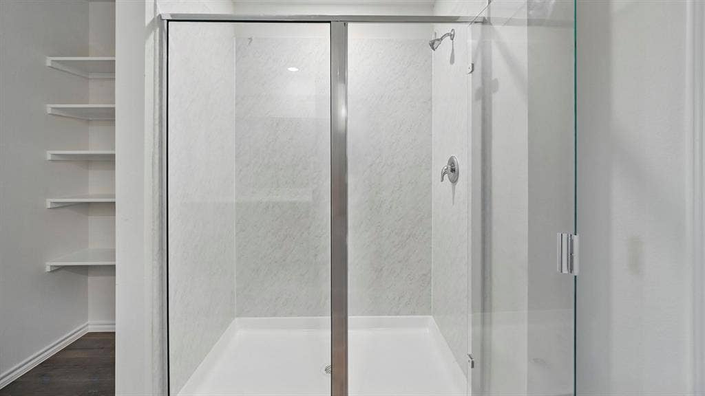 181 Brooks Street, Bullard, TX 75757 Glass-enclosed shower with a chrome shower head and handle, white shower pan, and built-in shelving
