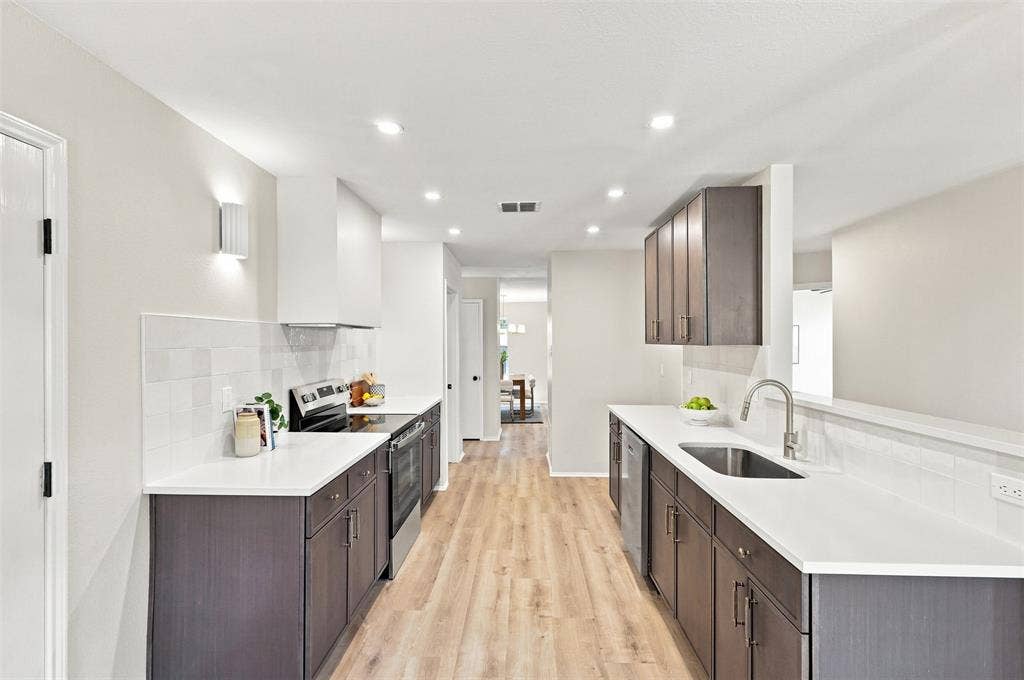 1406 Quail Meadow Drive, Wylie, TX 75098 Galley kitchen with wood-finish flooring, dark wood-finish cabinetry, white countertops, and white subway tile backsplash