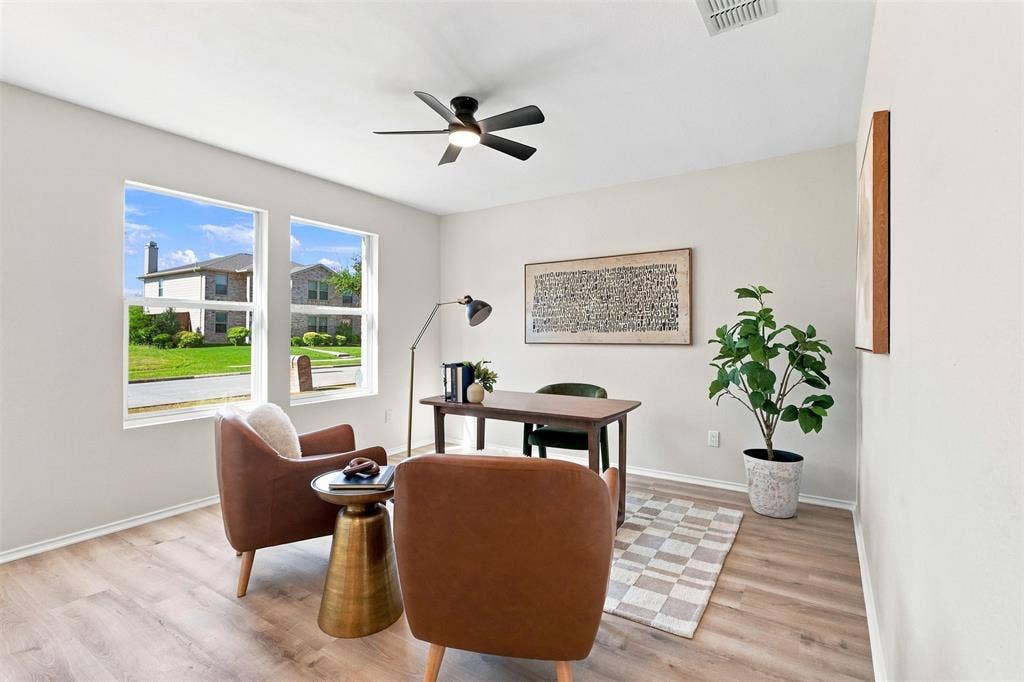1406 Quail Meadow Drive, Wylie, TX 75098 Spacious room featuring two large windows, wood-finish flooring, a ceiling fan with integrated lighting, and neutral wall tones