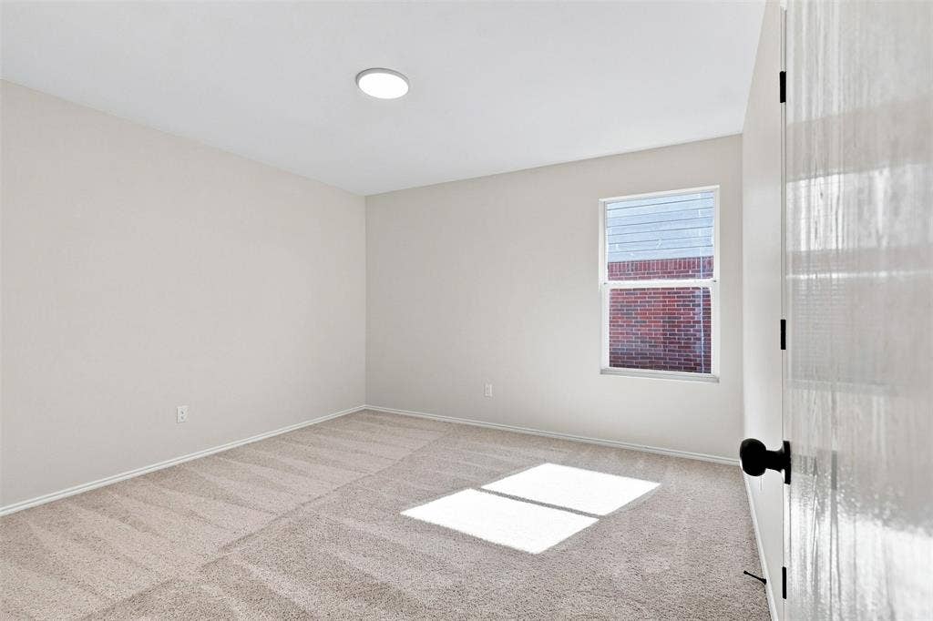 1406 Quail Meadow Drive, Wylie, TX 75098 Neutral wall paint, textured carpeting, modern flush-mount lighting, single window with blinds, and a white door with black hardware