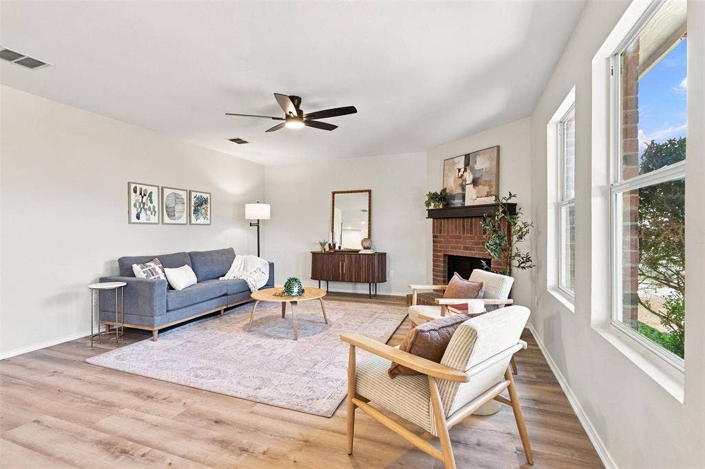 1406 Quail Meadow Drive, Wylie, TX 75098 Wood-finish flooring, brick fireplace, multiple windows, and a ceiling fan with integrated lighting