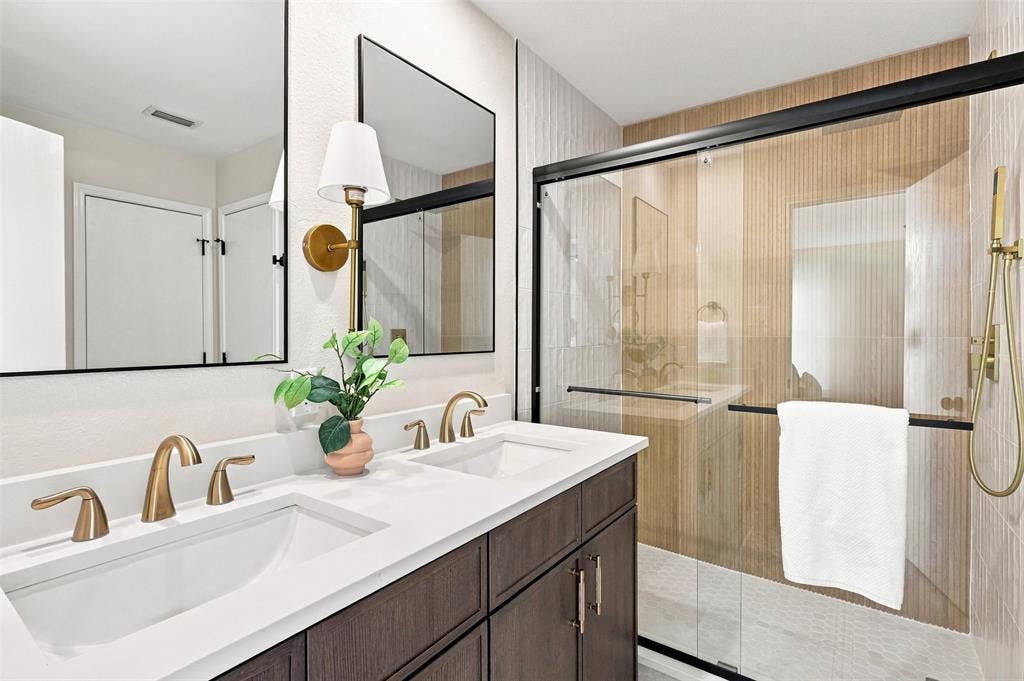 1406 Quail Meadow Drive, Wylie, TX 75098 Double vanity with integrated sinks, brushed gold fixtures, a glass-enclosed shower, and a built-in shower niche