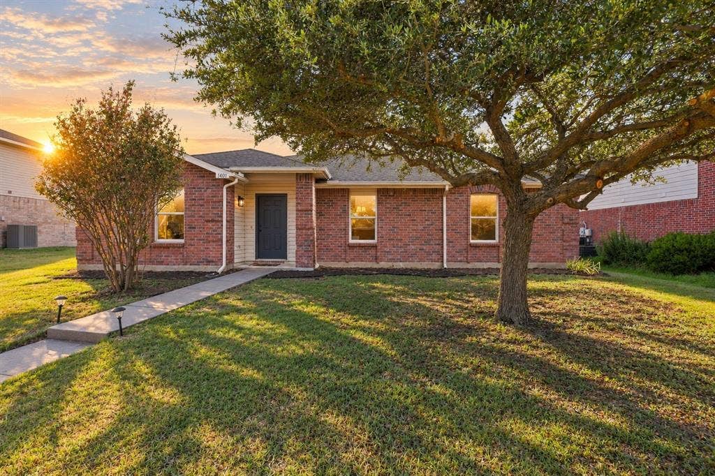 1406 Quail Meadow Drive, Wylie, TX 75098 Brick exterior with a dark entry door, a concrete walkway, and established landscaping