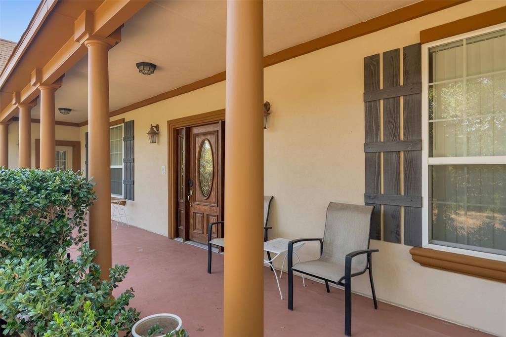 2720 Oates Drive, Mesquite, TX 75150 Front porch with multiple columns, wood-finish front door with oval glass insert, exterior wall sconce, and decorative window shutters