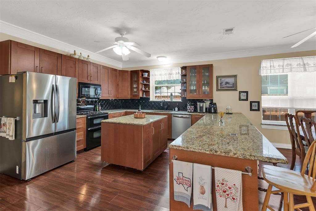 2720 Oates Drive, Mesquite, TX 75150 Kitchen featuring wood-finish flooring, stainless steel appliances, granite countertops, wood cabinetry, and a central island