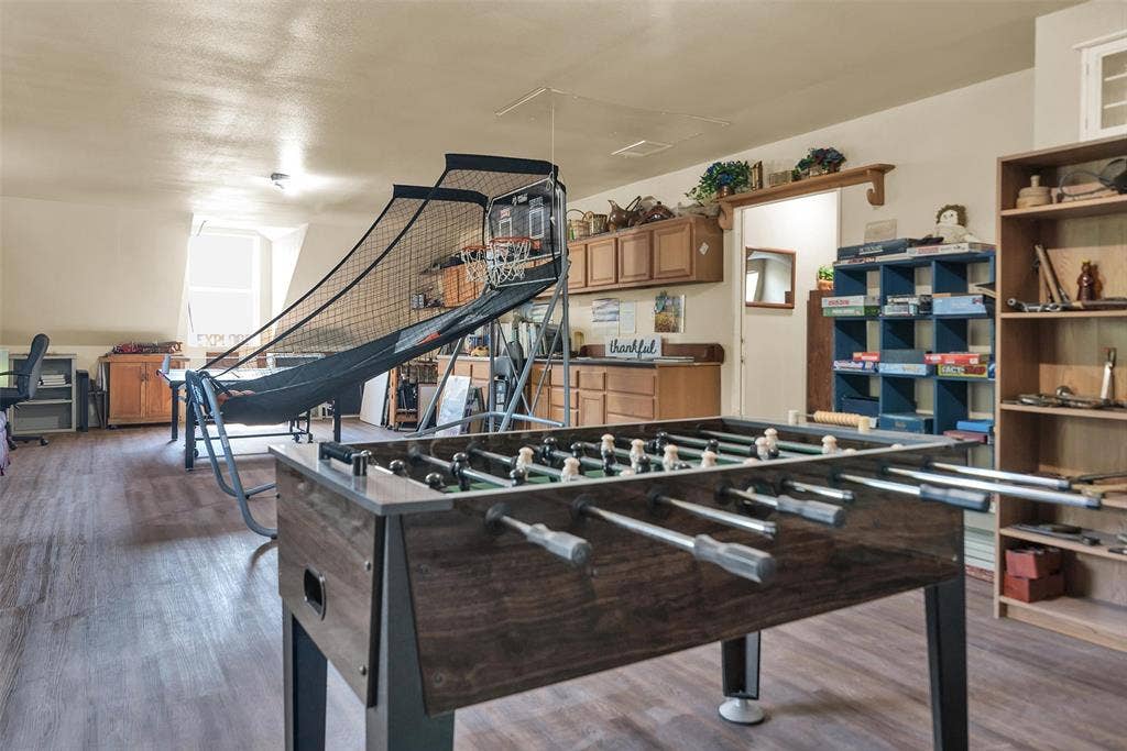 2720 Oates Drive, Mesquite, TX 75150 Wood-finish flooring throughout a spacious room, featuring a built-in wooden shelving unit, a built-in blue storage unit, and wood-finish cabinetry