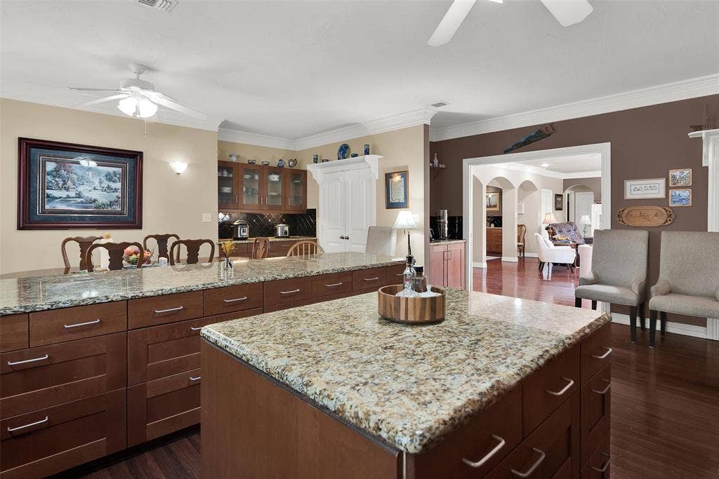 2720 Oates Drive, Mesquite, TX 75150 Kitchen featuring two granite-topped islands, rich wood-finish cabinetry, built-in appliances, and hardwood flooring