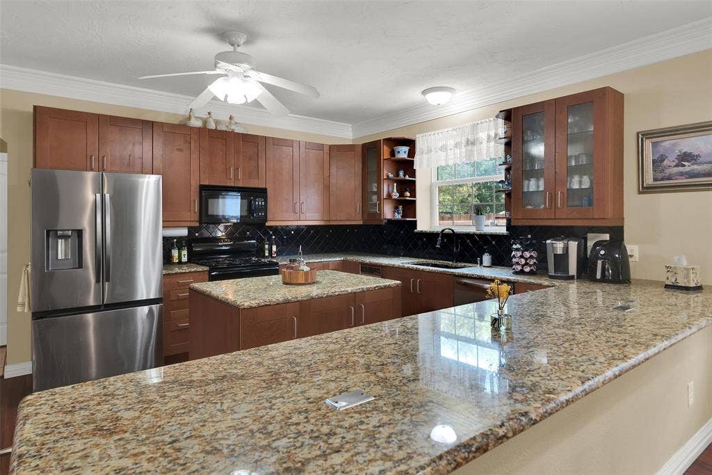 2720 Oates Drive, Mesquite, TX 75150 Kitchen featuring wood cabinetry, stainless steel appliances, a center island, and granite countertops