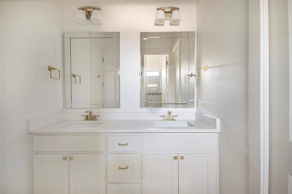 Dual vanity with white cabinetry, gold-toned hardware, and rectangular undermount sinks