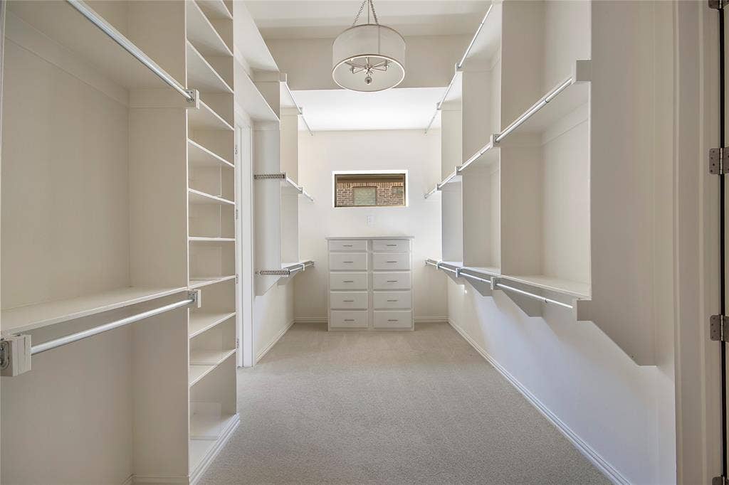 Walk-in closet with extensive built-in shelving, multiple hanging rods, a built-in dresser, and a central light fixture