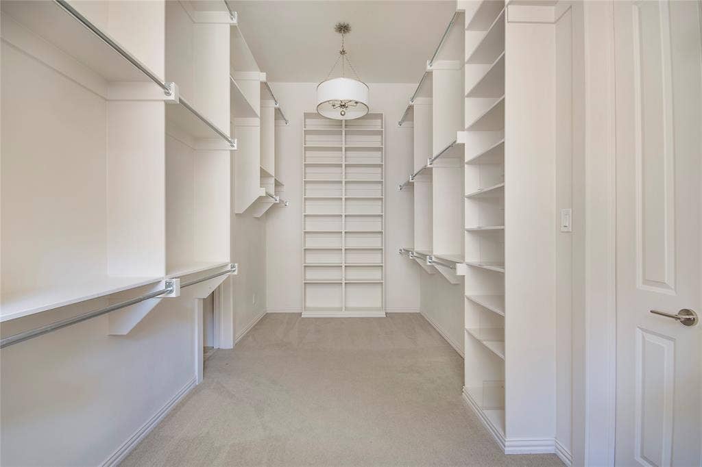 Walk-in closet featuring extensive built-in shelving, multiple hanging rods, recessed lighting, and carpet flooring