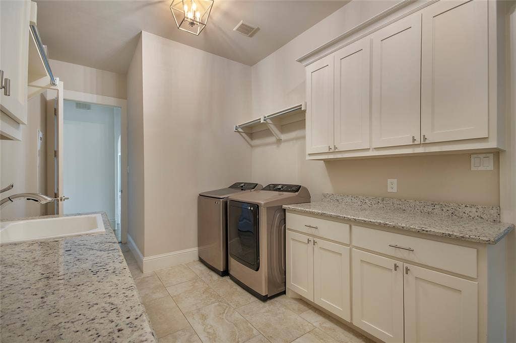 Light-toned cabinetry with stainless steel hardware, a utility sink with a pull-down faucet, and a light-toned countertop