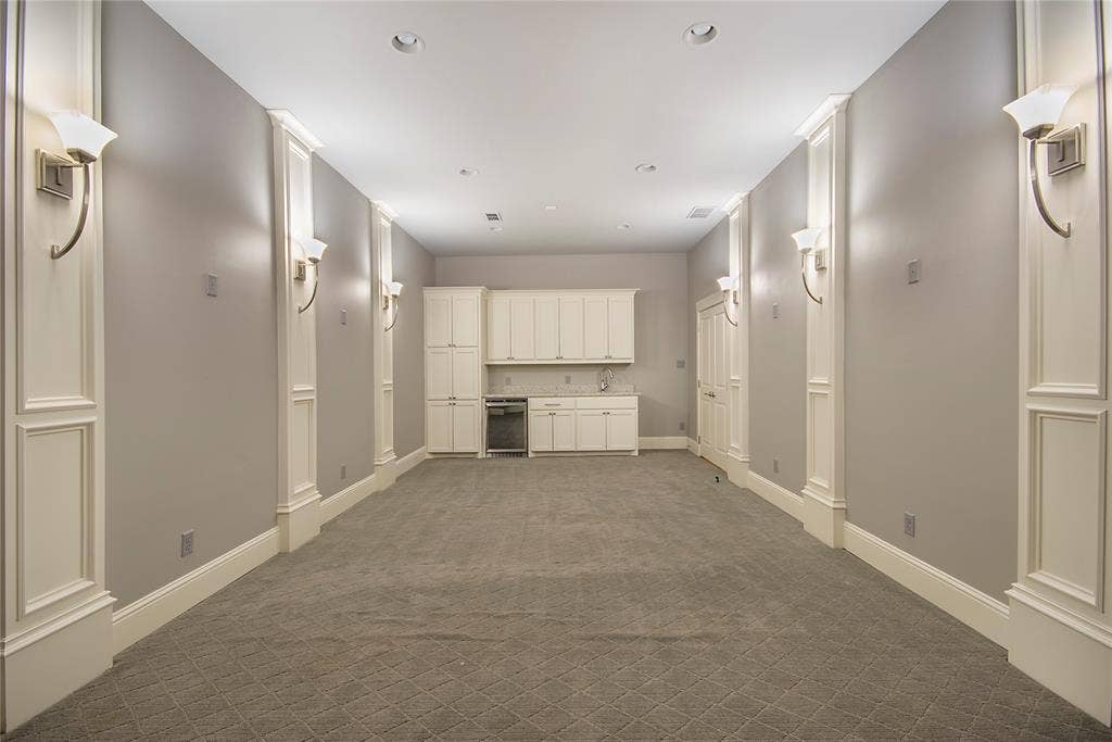 Recessed lighting, wall sconces, built-in cabinetry, integrated beverage refrigerator, and patterned carpet flooring