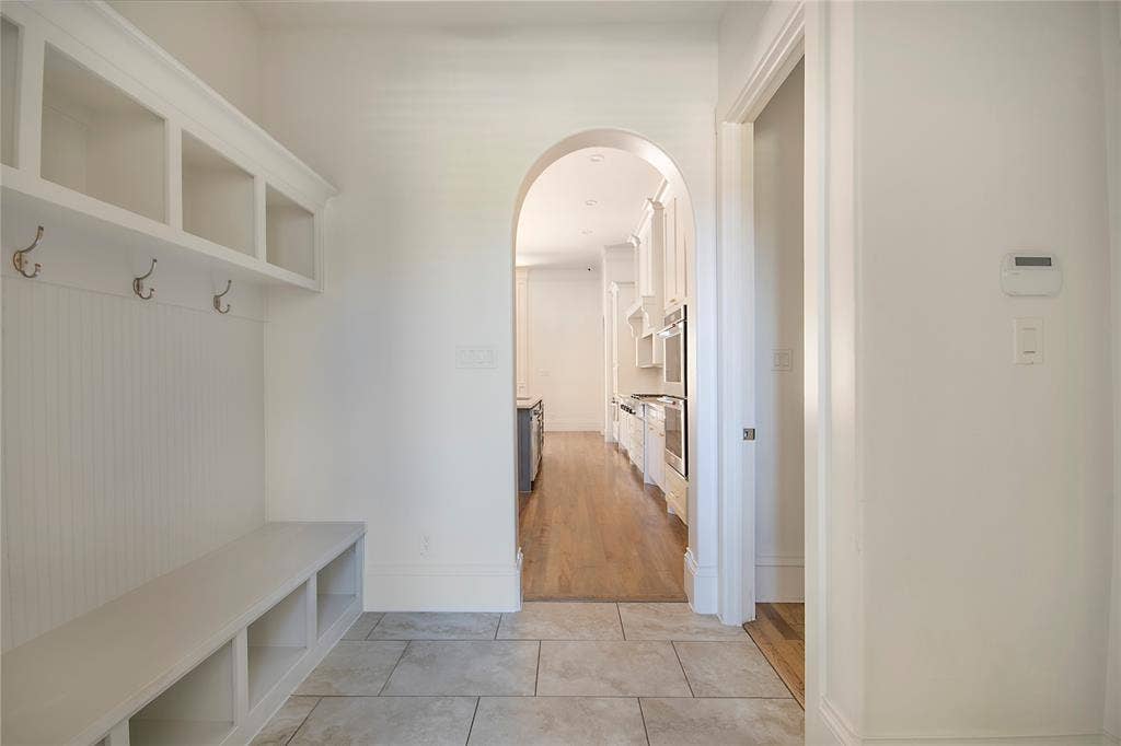 Built-in bench with storage, beadboard paneling, and an arched entryway