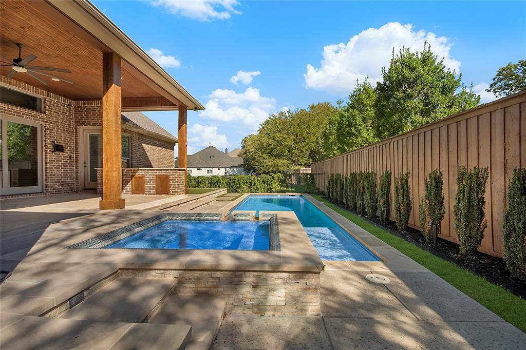 Expansive outdoor area featuring a swimming pool, integrated spa, and a covered patio with a wood-finish ceiling and a ceiling fan