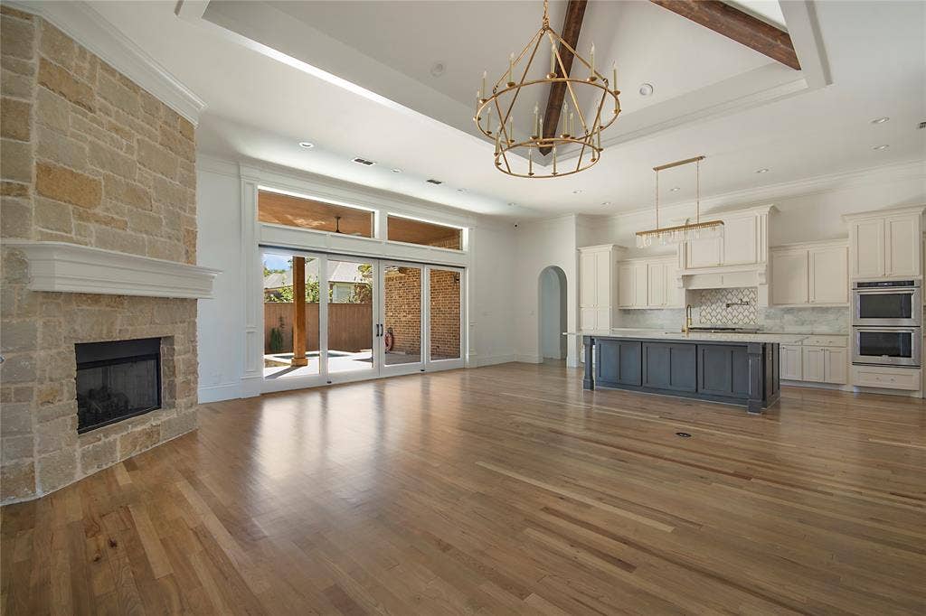 Spacious living area with wood flooring, stone fireplace, and a large sliding glass door