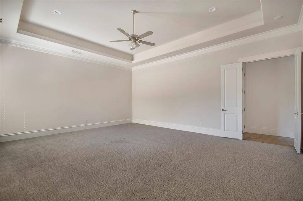 Recessed lighting, ceiling fan, tray ceiling, crown molding, and neutral-toned carpeting