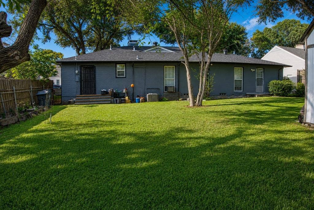 5012 Wateka Drive, Dallas, TX 75209 Expansive backyard featuring a manicured lawn, established trees, privacy fencing, and a utility shed