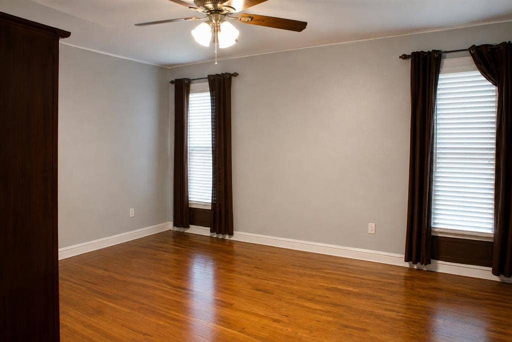 5012 Wateka Drive, Dallas, TX 75209 Hardwood flooring throughout, neutral wall paint, two windows with blinds, and a ceiling fan with integrated lighting