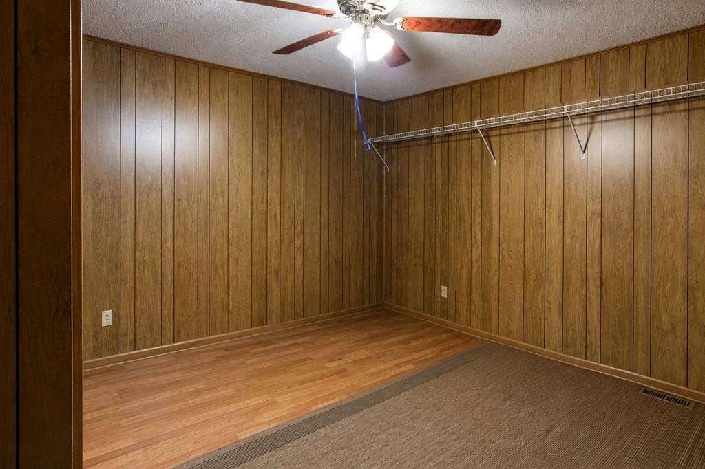 5012 Wateka Drive, Dallas, TX 75209 Ceiling fan with light fixture, wood-finish wall paneling, mixed flooring with wood-finish and carpet, wire shelving system