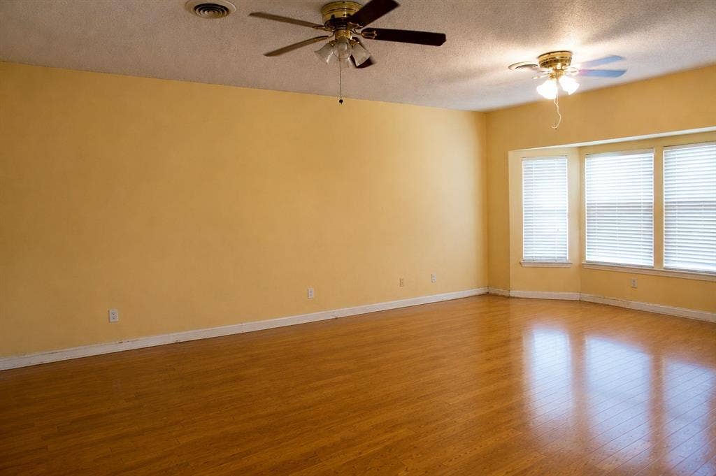 5012 Wateka Drive, Dallas, TX 75209 Wood-finish flooring with baseboards, bay window with blinds, and two ceiling fans with integrated lighting