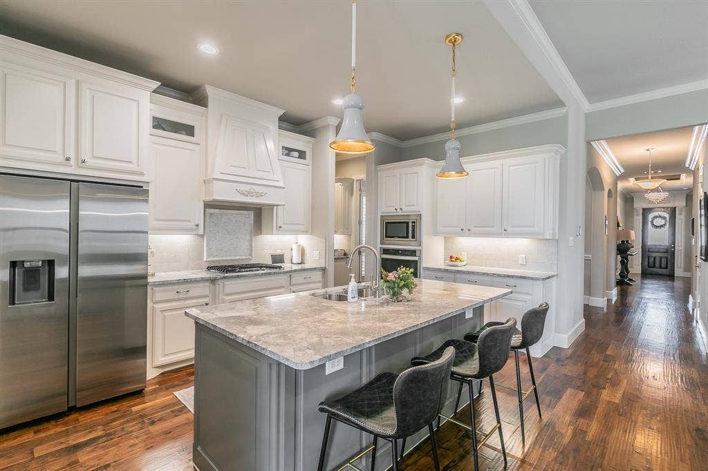 313 Elkhorn Trail, Keller, TX 76248 Gourmet kitchen featuring white cabinetry, stainless steel appliances, a large center island with seating
