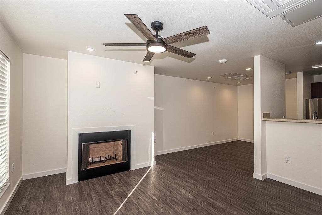 3022 Forest Lane, #116, Dallas, TX 75234 living room has wood burning fireplace and a healthy amount of sunlight