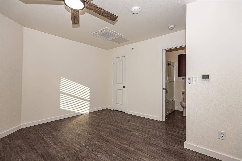 3022 Forest Lane, #116, Dallas, TX 75234 Bedroom with ceiling fan wood-style floors and ensuite bath - 2nd floor
