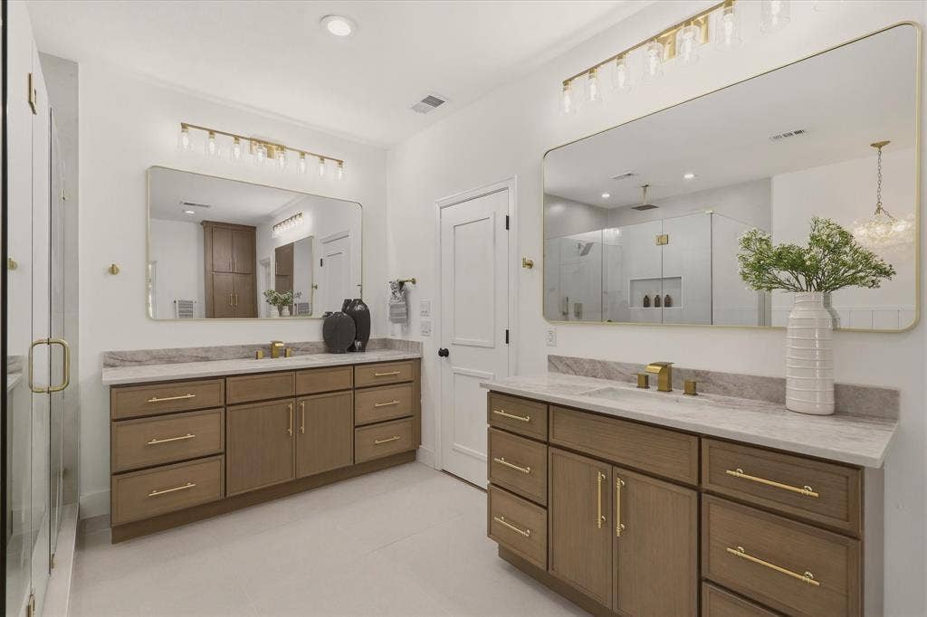 Dual vanity featuring wood-finish cabinetry and gold-tone hardware