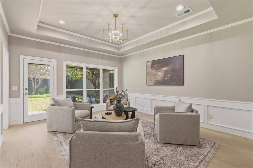 Tray ceiling with an ornamental chandelier, recessed lighting, wood-finish flooring, wainscoting, and large windows