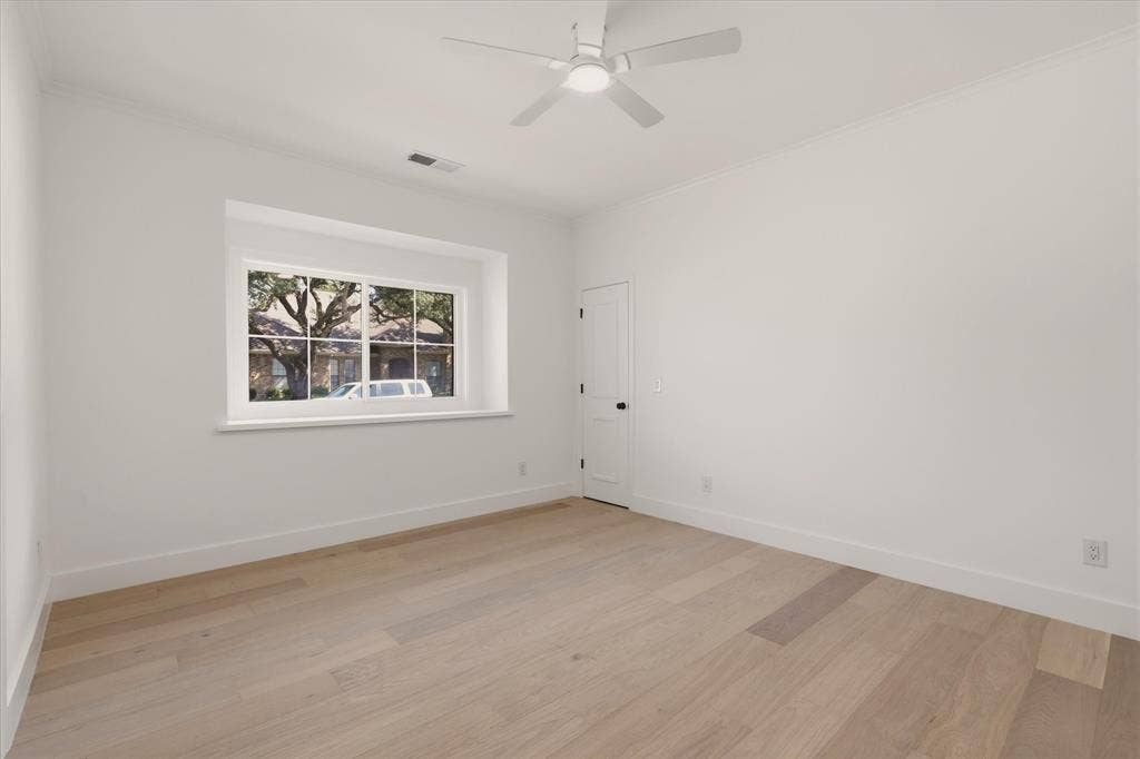 Recessed window with white trim, light wood-finish flooring, white walls, ceiling fan with integrated lighting, and crown molding