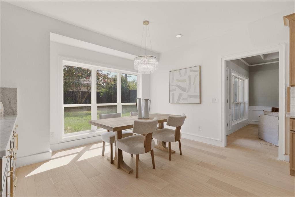 Recessed lighting, wood-finish flooring, crisp white walls, large window with backyard exposure, and a beaded chandelier