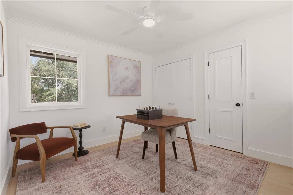 Light wood-finish flooring, white walls, and a ceiling fan with integrated lighting