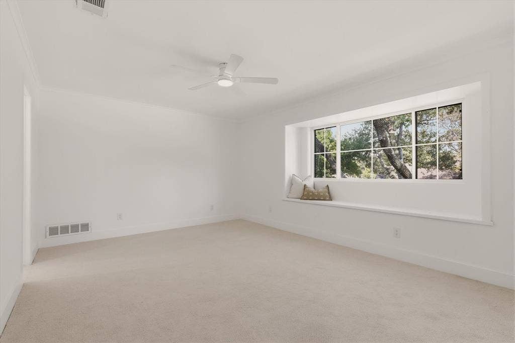 Expansive room with neutral carpet, large picture window, and a built-in window seat