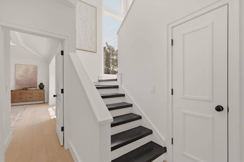 Staircase with contrasting risers and treads, open doorway, and a tall window