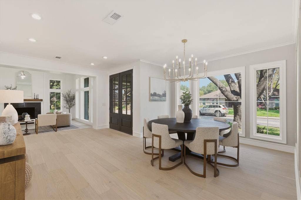 Expansive room featuring wood-finish flooring, recessed lighting, a fireplace with a dark mantel, multiple large windows, and a chandelier
