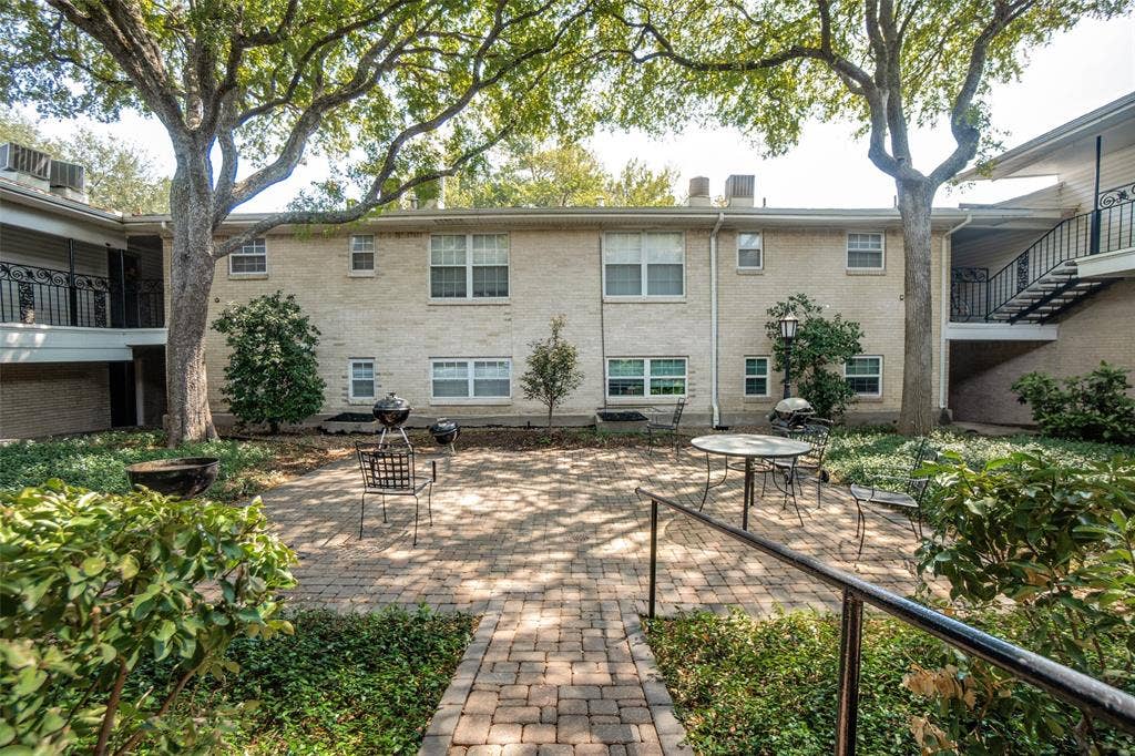 5818 E University Boulevard, #138, Dallas, TX 75206 Brick exterior building with multiple windows, a paved brick patio, mature trees, and established landscaping
