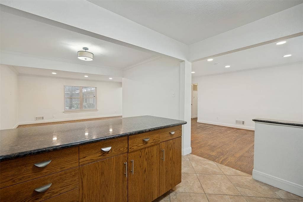 5818 E University Boulevard, #138, Dallas, TX 75206 Kitchen island with wood cabinetry, dark countertop, and brushed nickel hardware