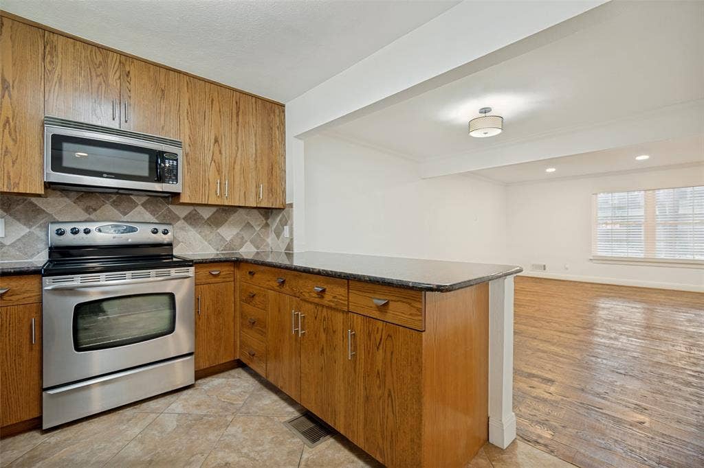 5818 E University Boulevard, #138, Dallas, TX 75206 Kitchen featuring wood-finish cabinetry, stainless steel appliances, and a tiled backsplash