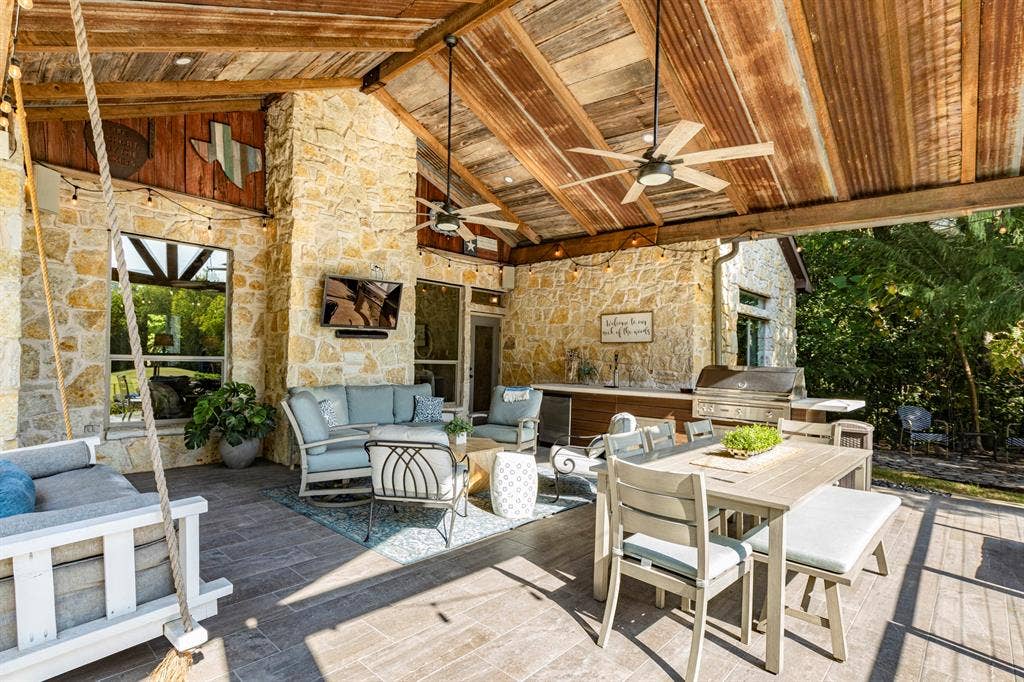6810 Trinity Falls Parkway, McKinney, TX 75071 Expansive covered patio featuring a stone exterior, wood-paneled ceiling, ceiling fans, and an outdoor kitchen with an integrated grill
