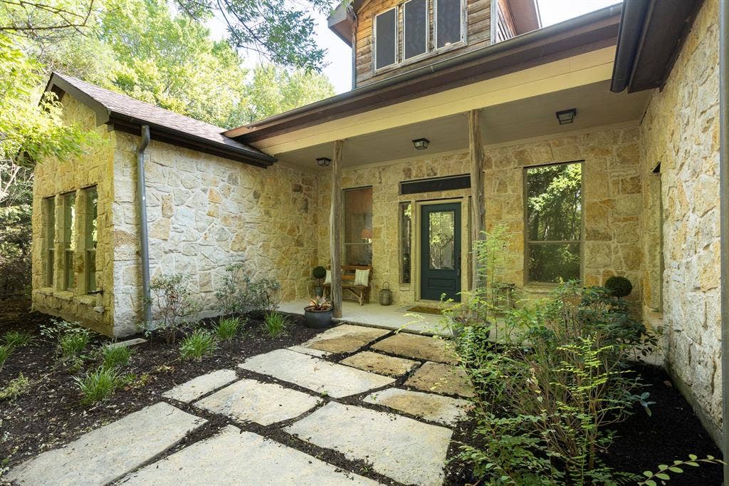 6810 Trinity Falls Parkway, McKinney, TX 75071 Stone exterior with a covered entry, dark paneled entry door, and multi-paned windows
